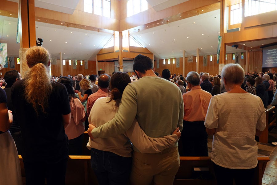 a couple solemnly embrace during Mass
